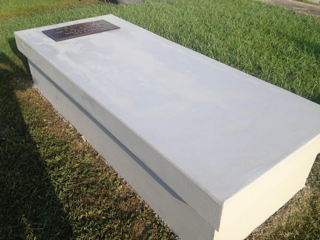 Before: A smooth, plain concrete vault with a bronze plaque, before texture coating.