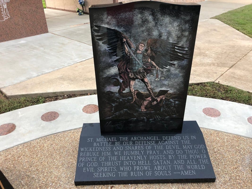 A black granite monument etched with St. Michael the Archangel above the prayer to St. Michael.