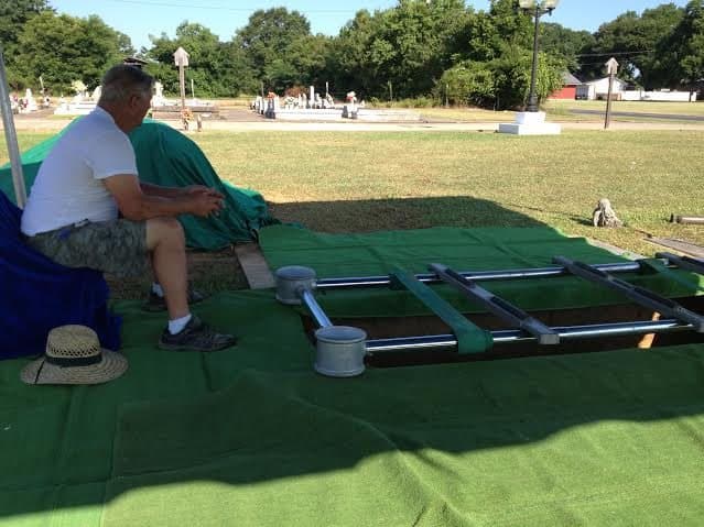 A worker preparing a grave with green grass carpet and a lowering device.