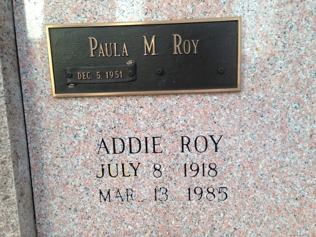 A pink granite crypt front with a bronze nameplate above an engraved name and dates.