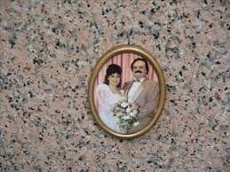 An oval porcelain wedding photograph in a bronze frame, set into pink granite.