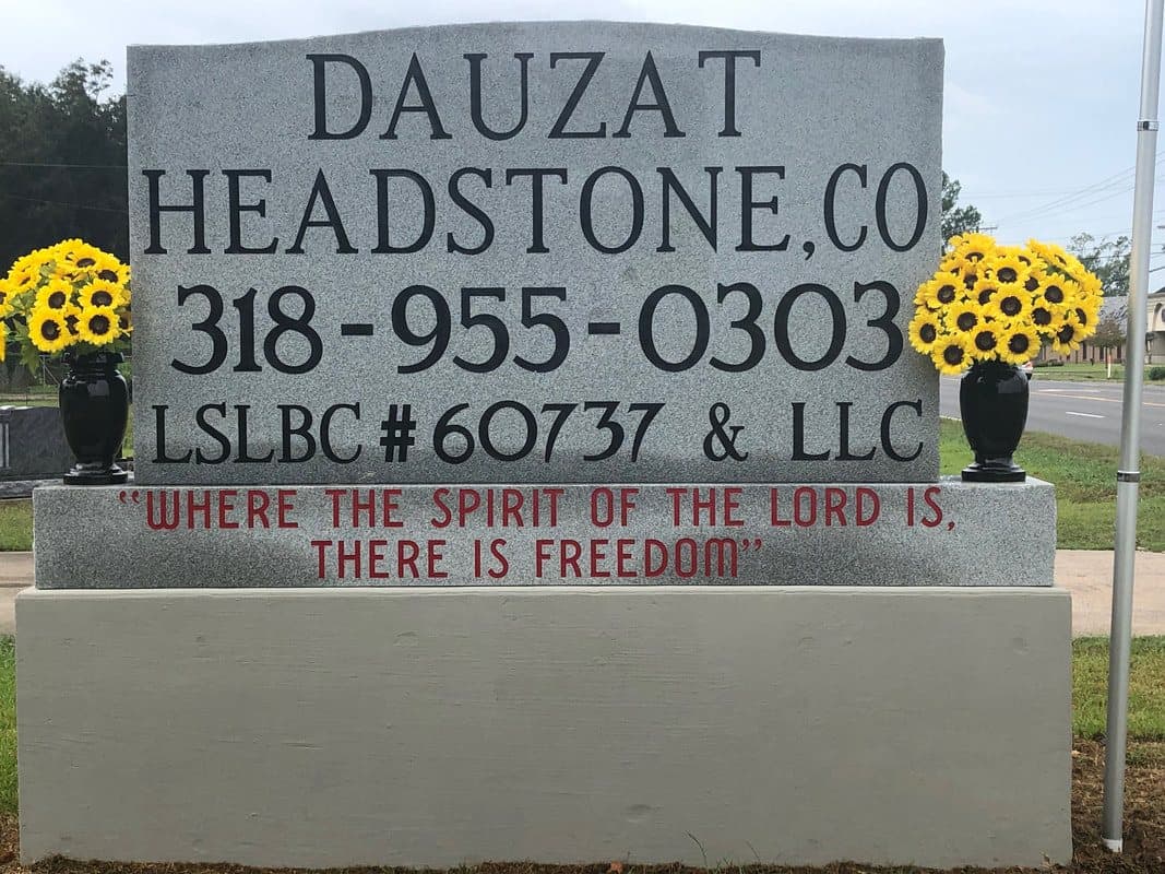 The Dauzat Headstone Co. sign in Alexandria, with sunflowers on each side and the line “Where the Spirit of the Lord is, there is Freedom.”