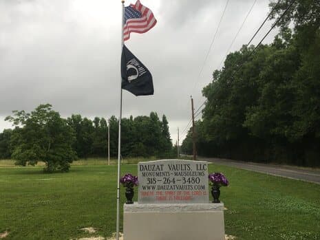 The Dauzat Vaults roadside sign on Highway 453 in Marksville, beneath an American flag and a POW/MIA flag.