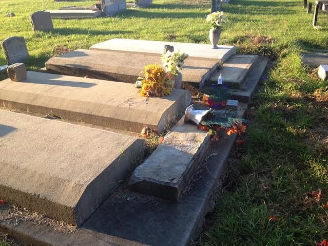 Concrete slabs poured over a row of graves, with headstones and flowers.
