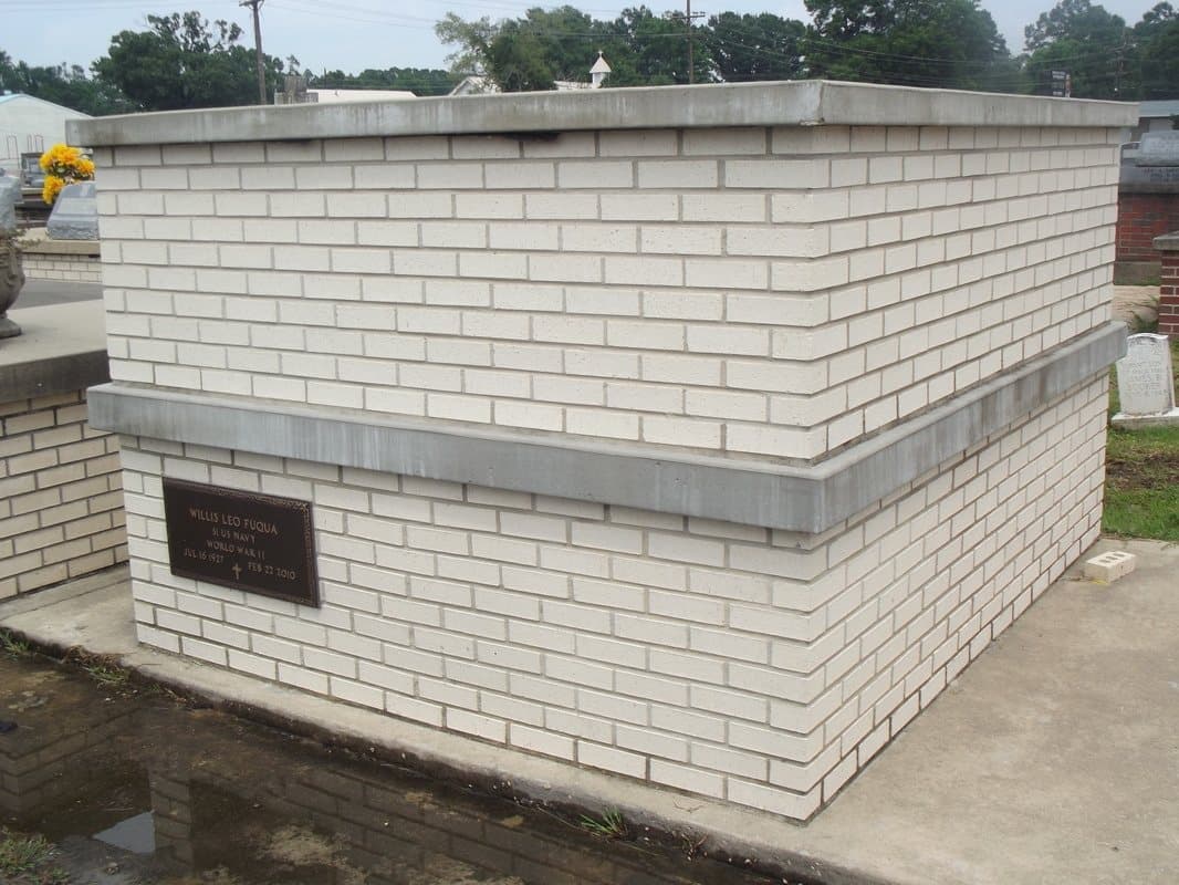 A white brick tomb with a bronze plaque.