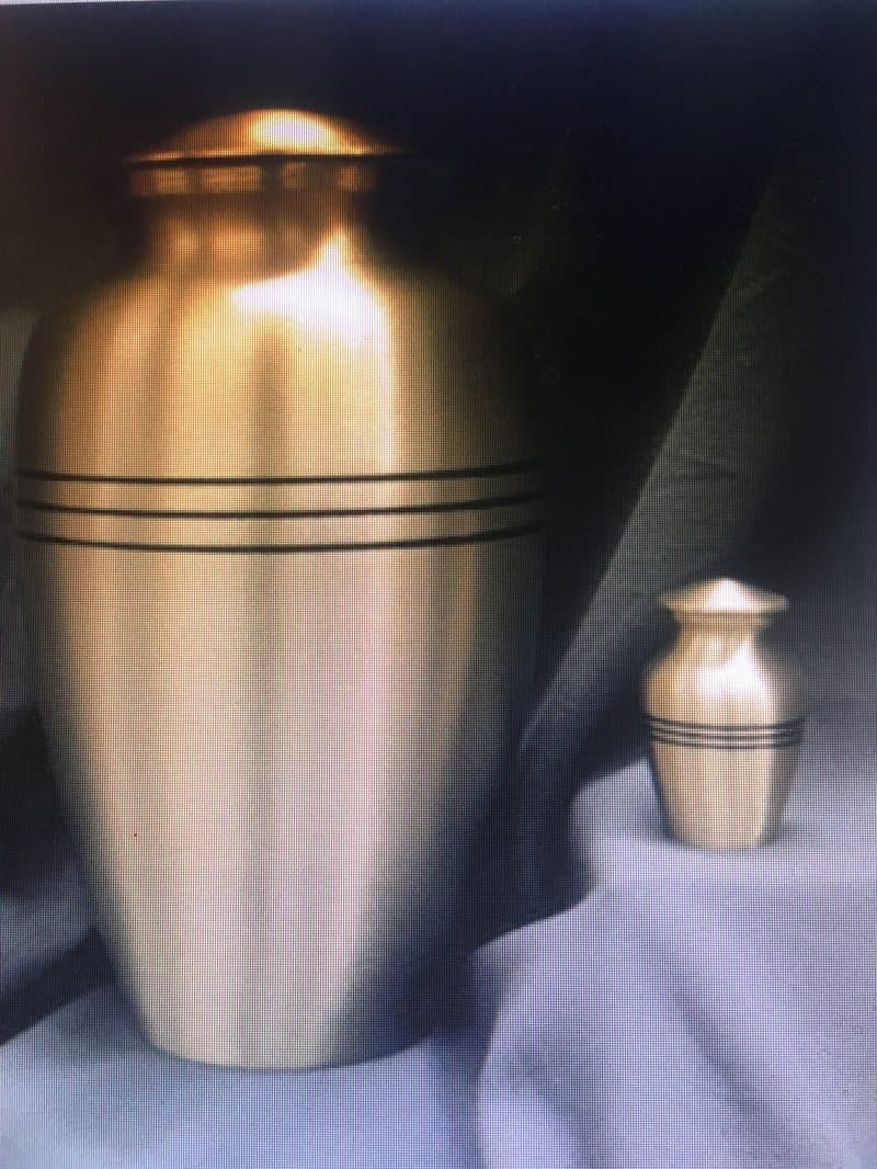 A brushed brass cremation urn with a matching small keepsake urn.