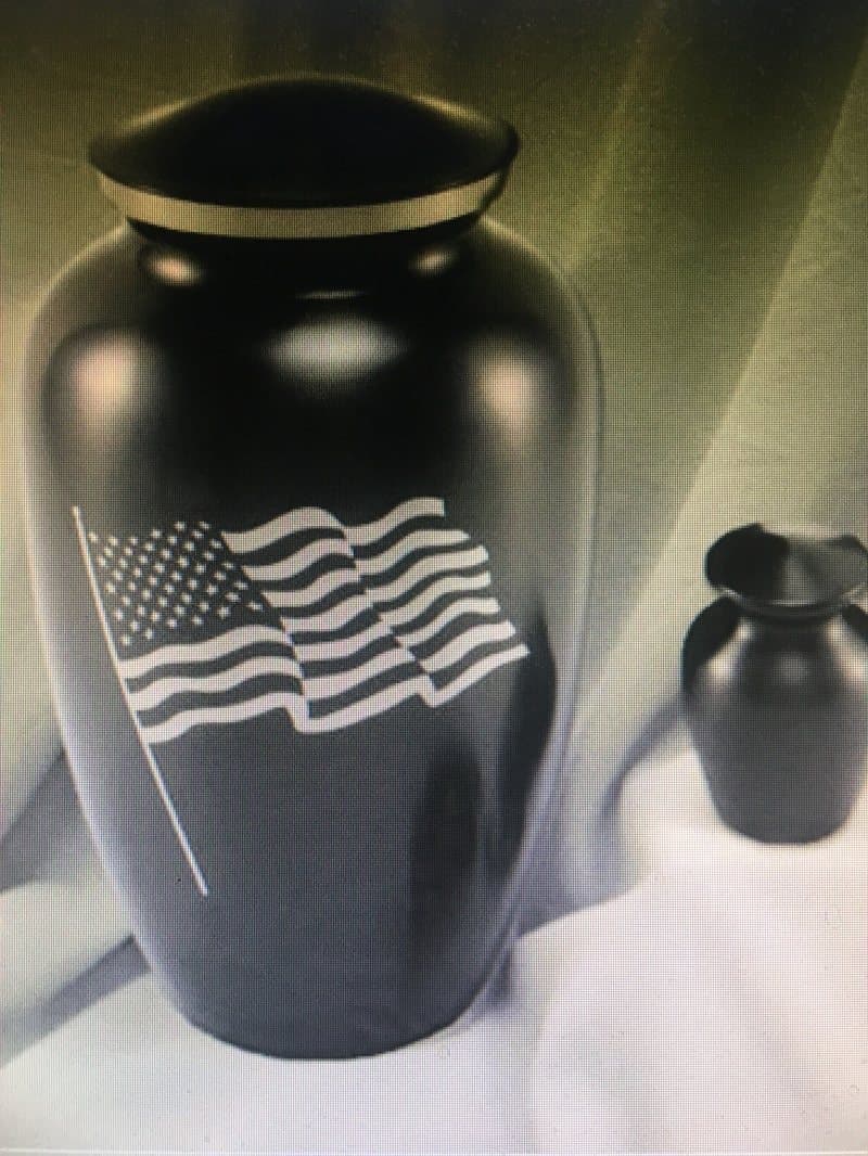 A black cremation urn engraved with an American flag, beside a matching keepsake urn.
