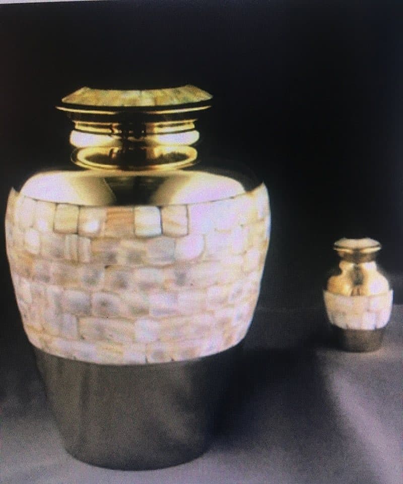 A cremation urn with a mother-of-pearl band, beside a matching keepsake urn.