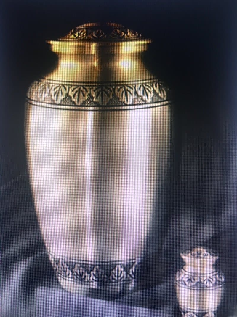 A pewter-finish cremation urn with an embossed band, beside a matching keepsake urn.