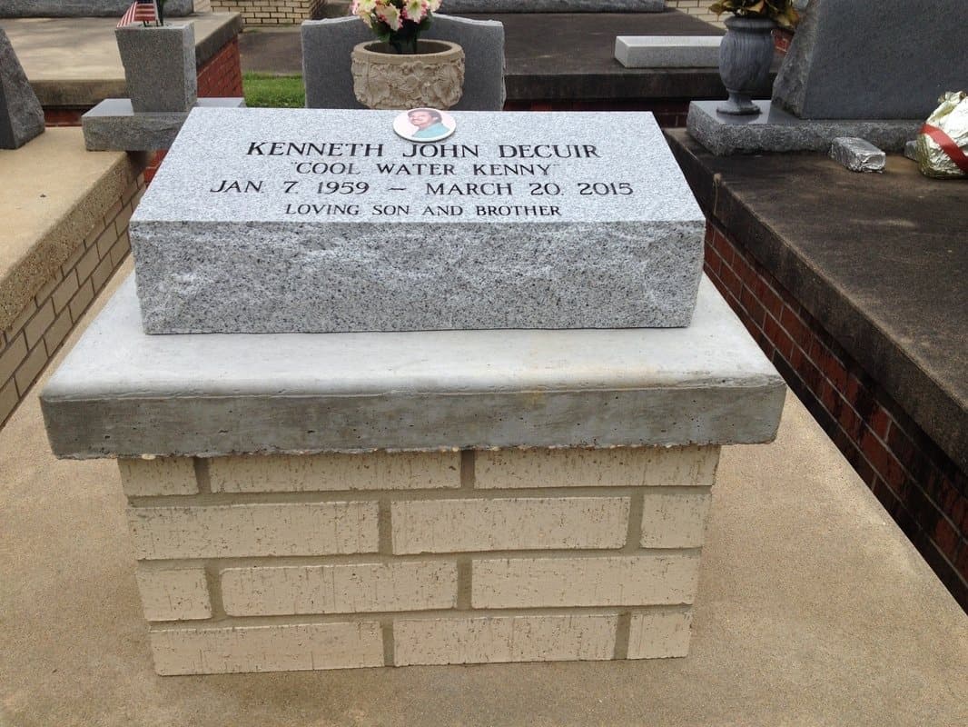 A white brick urn vault capped with an engraved gray granite block.