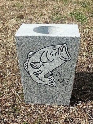 A gray granite vase etched with a jumping bass.