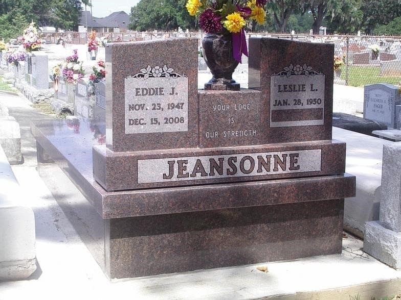 A red granite wrap and cap around a family grave, with a double headstone on top.
